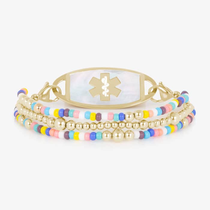 Oval medical ID tag with white inlay and medical symbol attached to a gold tone beaded bracelet with colorful seed beads.