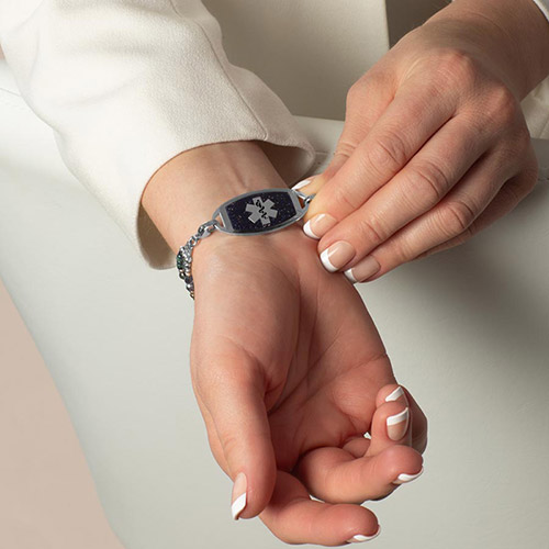 Phoebe Medical Alert Bracelet in Silver with layered strands of grey, blue, and metallic beads, shown on wrist with Lauren’s Hope medical ID tag