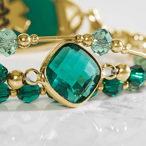 Close-up of bracelet details on Laurel Medical Alert Bracelet, highlighting green-blue faceted crystals and a gold bezel-set emerald crystal