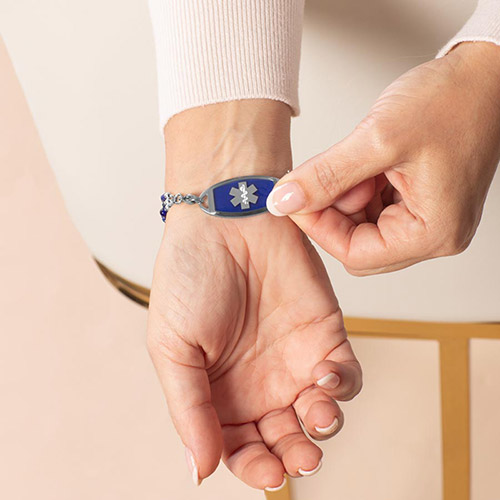 Woman showing mix and match medical ID alert tag with deep blue lapis inlay and silver medical caduceus symbol
