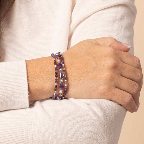 Woman with arms crossed wearing purple and lavender beaded medical alert bracelet