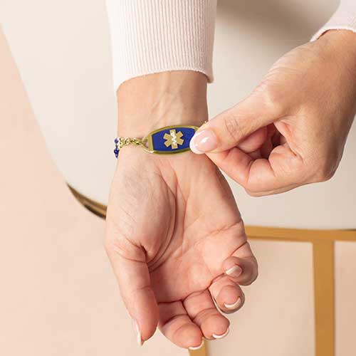 Woman showing mix and match medical ID alert tag with deep blue lapis inlay and gold medical caduceus symbol