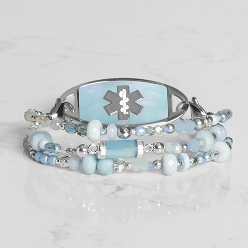 Flat lay of the silver Dewdrop medical ID bracelet with a blue mother-of-pearl inlay, highlighting its elegant and lightweight design.