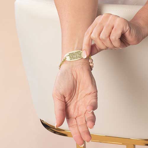 Woman displaying the custom, laser, engraving on her gold medical ID tag.