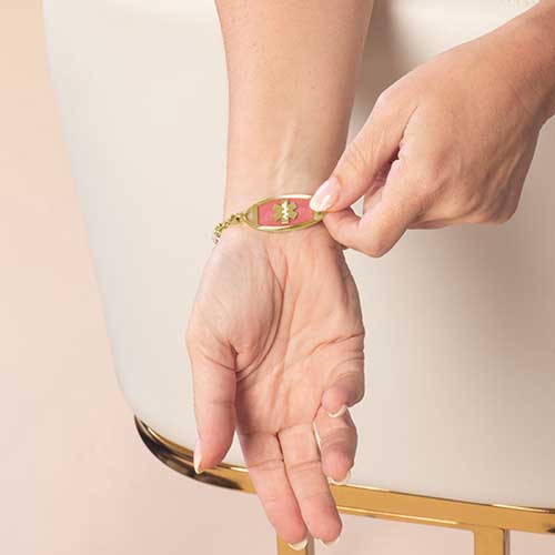 Woman displaying her pink stone inlaid gold medical ID tag.