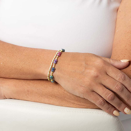Model wearing the Lisa bracelet, holding wrist palm-up to show the pink-inlay medical ID tag with gold medical symbol.