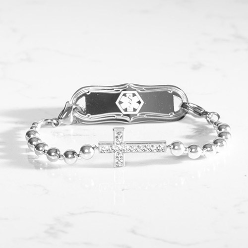 Faith Silver Medical ID Bracelet with Engravable Tag – Elegant silver beaded medical alert bracelet featuring a crystal-studded cross and scalloped-edge stainless steel ID tag with white medical symbol.
