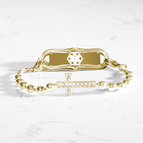 Faith-inspired gold medical ID bracelet for women, featuring a bold crystal cross centerpiece, smooth gold beads, and an elegant gold ID tag with engraved caduceus symbol.