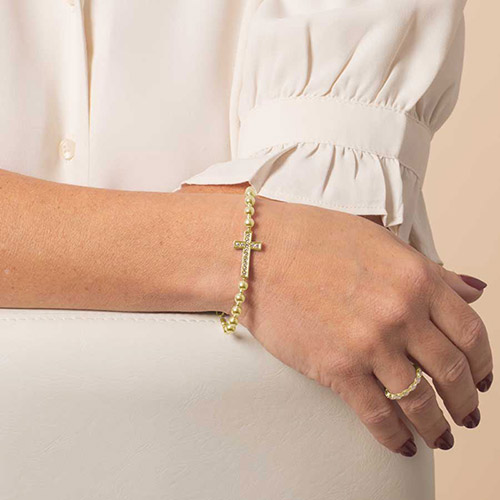 Elegant gold beaded medical ID bracelet with crystal cross, styled with a white blouse and matching ring