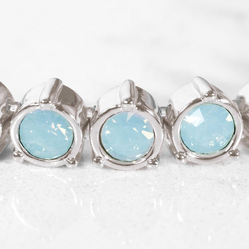 Detail view of round-cut blue opal crystals in polished silver-tone settings, showcasing the intricate bezel-style link design.
