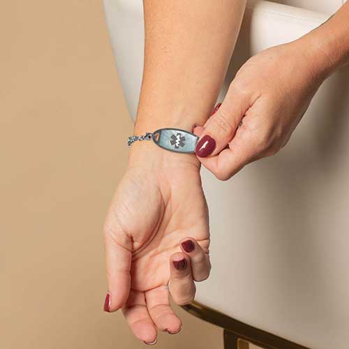 Woman displaying her blue mother of pearl inlaid medical ID.