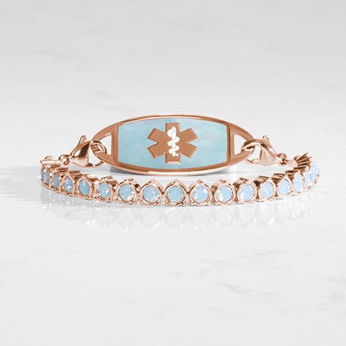 Luna Blue Opal medical ID bracelet in rose gold with shimmering opal inlay tag and blue opal crystal tennis strand, shown on marble.