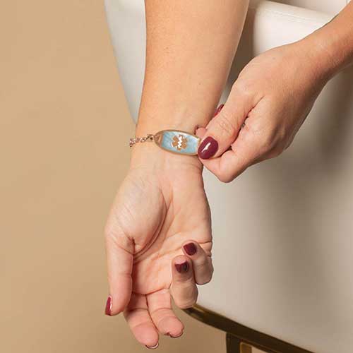Woman displaying her blue mother of pearl inlaid medical ID.