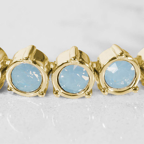 Close-up of gold bracelet links with round blue opal crystals in bezel settings