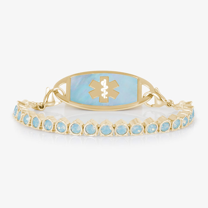 Product photo of gold medical ID bracelet with blue opal crystals and an iridescent inlay tag on white background