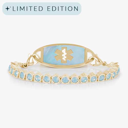 Product photo of gold medical ID bracelet with blue opal crystals and an iridescent inlay tag on white background