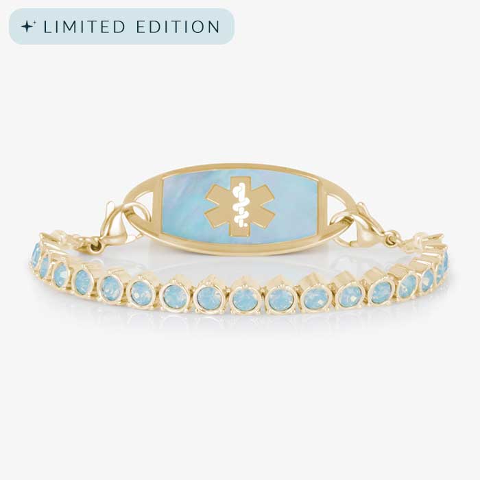 Product photo of gold medical ID bracelet with blue opal crystals and an iridescent inlay tag on white background