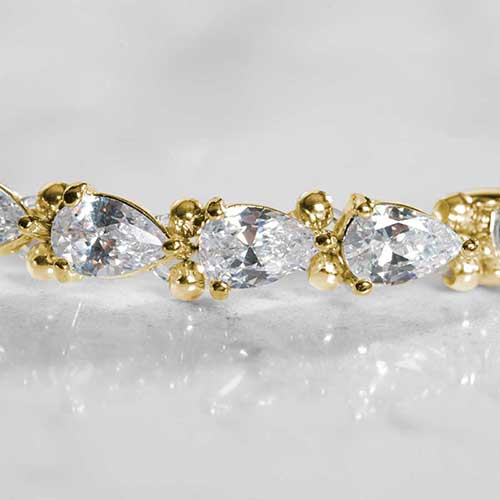 Close-up view of teardrop-cut cubic zirconia stones in gold prong settings on a women's medical ID bracelet.