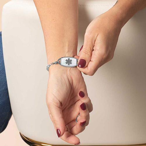 Silver Jackie medical ID bracelet with mother-of-pearl inlay and silver caduceus symbol, shown on wrist for clarity.