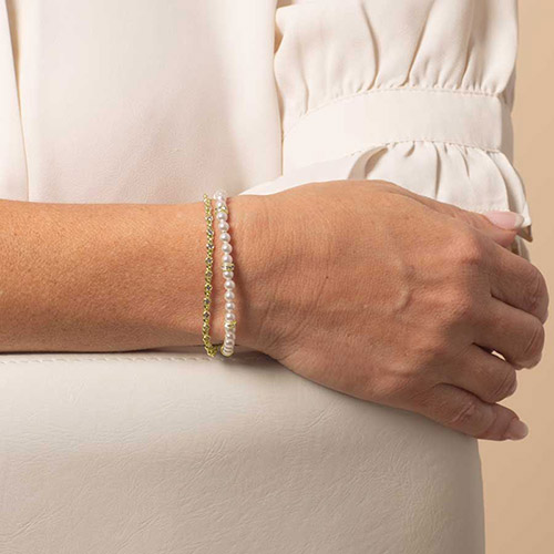 Close-up of a woman wearing a dual-strand bracelet with white pearls and a gold chain for a layered, elegant medical ID look.