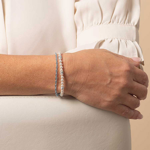 Model wearing a two-strand bracelet featuring freshwater pearls and a silver chain for a sleek, layered medical ID style.