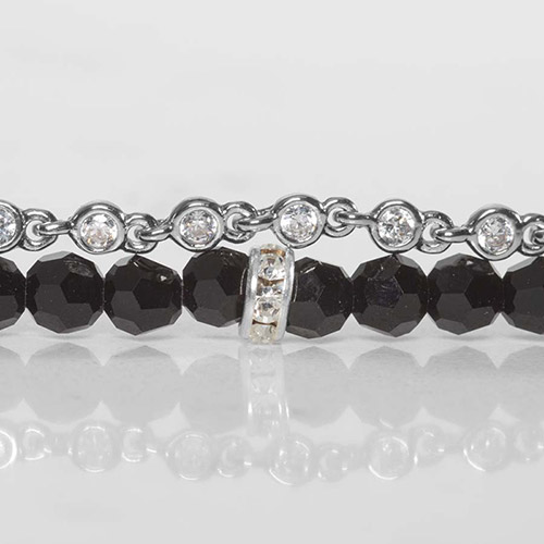 Zoomed-in view of the bracelet strands showing faceted black beads accented by a silver rhinestone ring and a top strand of bezel-set clear crystals linked by polished stainless steel.