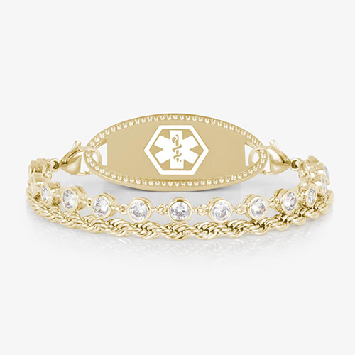 A gold-tone medical ID bracelet featuring two chains—one rope-style and one with bezel-set clear crystals—attached to a polished oval medical ID tag with a white Star of Life emblem. Displayed on a white background.