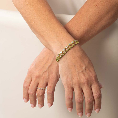Lifestyle image of a woman wearing the gold Arden bracelet stacked for a layered look with both twisted chain and CZ strands.