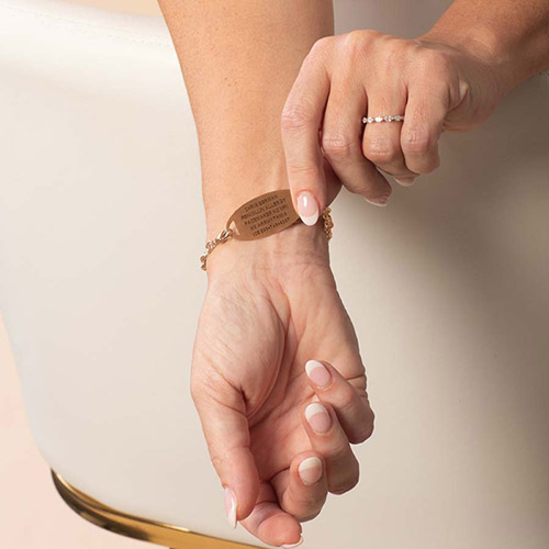 Woman displaying the underside of a rose gold medical ID bracelet with personalized engraving.