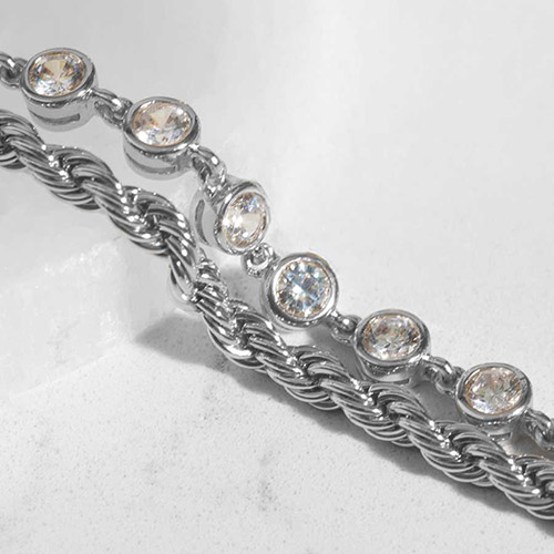 Close-up of the Arden Silver medical ID bracelet strands, featuring a dual design of twisted rope chain and bezel-set clear crystals in a polished silver finish, shown resting on a light stone surface.