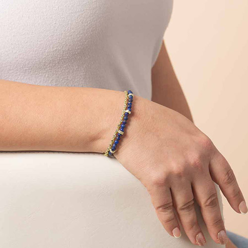 Woman wearing a gold and blue beaded medical ID bracelet with a hidden tag, combining elegant jewelry design with discreet medical safety for women.