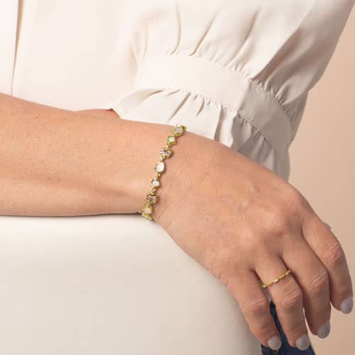 Model wears a gold-tone medical ID bracelet with alternating opalescent and light pink stones and a mother-of-pearl ID tag.
