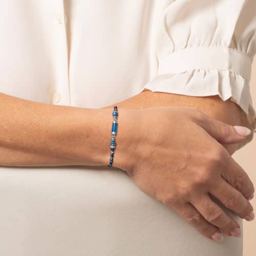 Model wears a blue beaded medical ID bracelet with silver-tone accent beads and a blue center bead on the wrist.