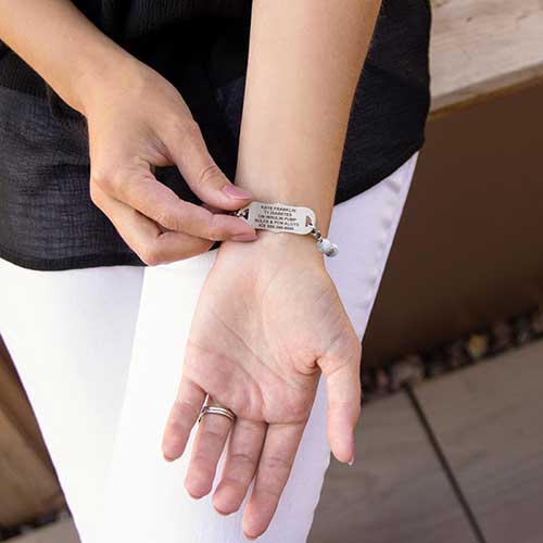 Woman showing premium laser engraving on stainless steel medical ID tag.