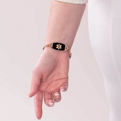 Woman wearing rose gold and black medical ID tag