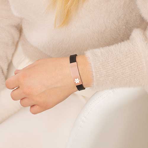 Woman wearing black silicone medical ID bracelet with rose gold tone stainless steel medical ID tag.