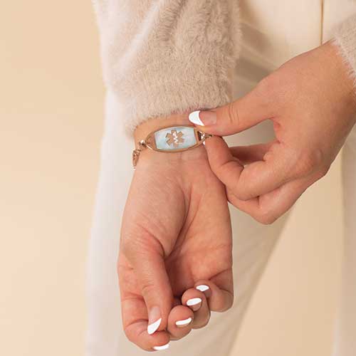 Woman wearing rose gold tone stainless steel medical ID tag with mother of pearl inlay.