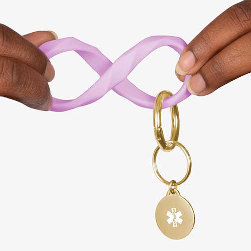 Woman twisting the lilac faceted silicone key ring wristlet with gold tone medical alert charm.